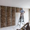 Construction site close up with workers making dry wall and implementing glass wool Earthwool-Acoustic.